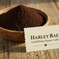 Wooden bowl of coffee grounds with a Harley Rae Coffee label on a wooden surface