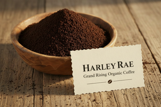 Wooden bowl of coffee grounds with a Harley Rae Coffee label on a wooden surface