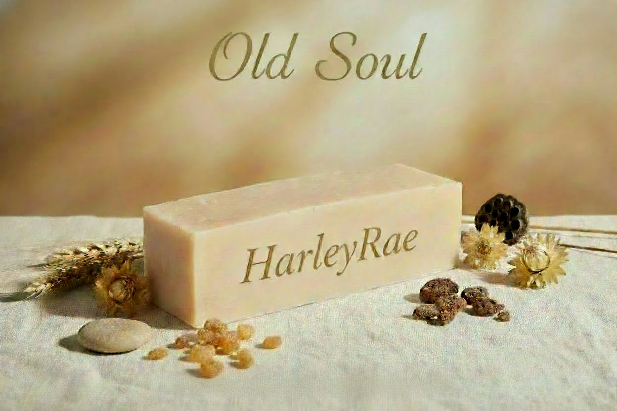 Bar of soap with 'Old Soul' and 'HarleyRae Wellness' branding on a textured surface with decorative elements.