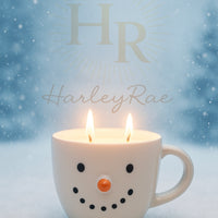 Snowman-shaped candle with Toasted Marshmallow Scent in a mug with 'HR HarleyRae' branding against a snowy background.