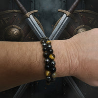 A bracelet made with tigers eye and hematite stones, wrapped around an arm.